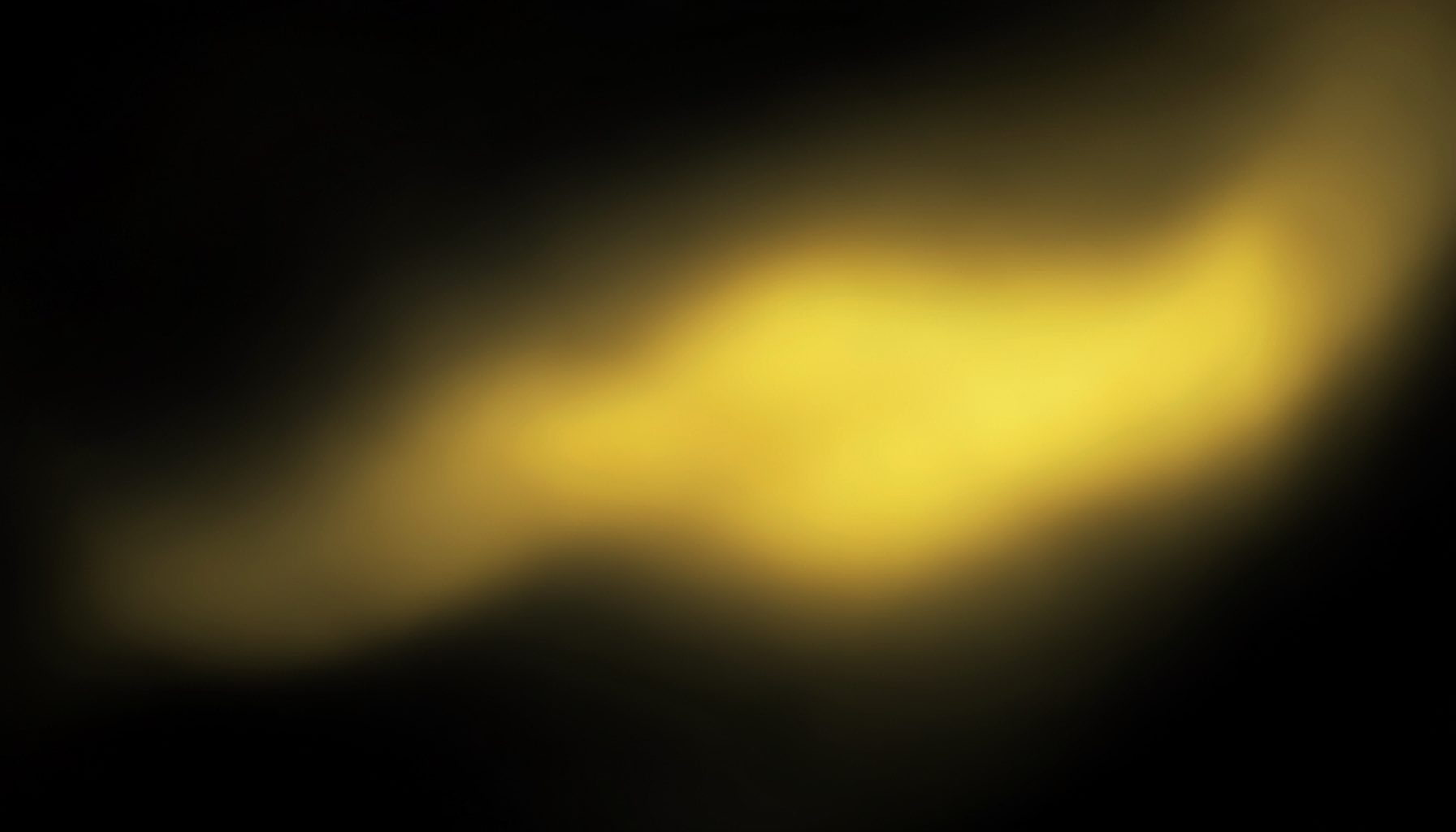 Abstract gradient composition in deep charcoal and warm gold tones, with a smooth luminous transition across a dark atmospheric backdrop